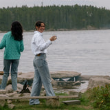 Three friends sharing drinks on the rocks by the water, one in the white Darty Popover
