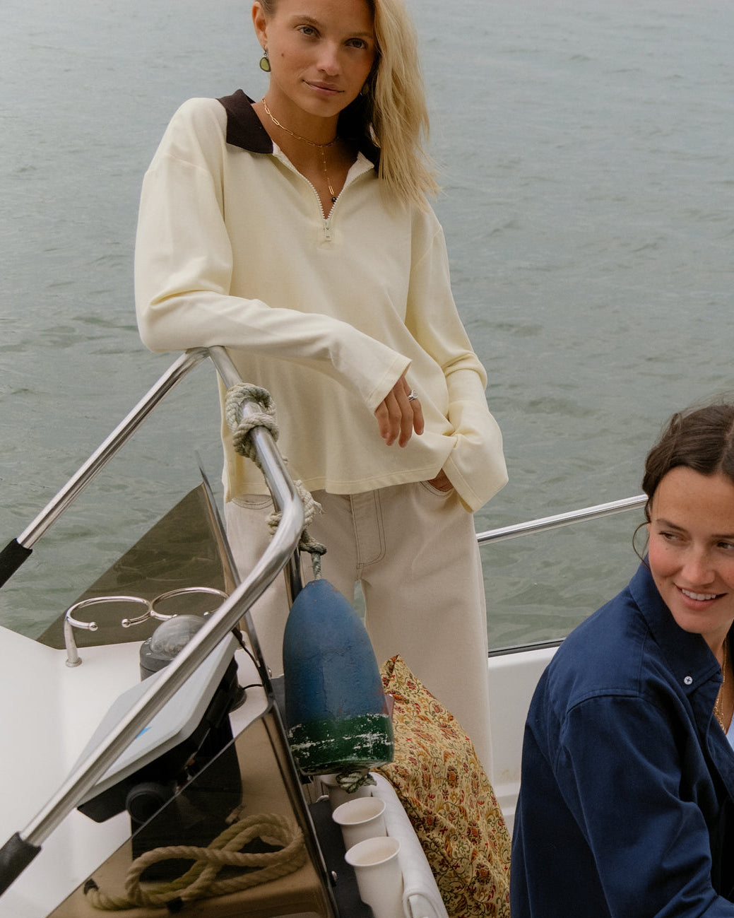 Two women on a boat wearing off-white and navy By Dusk tops.